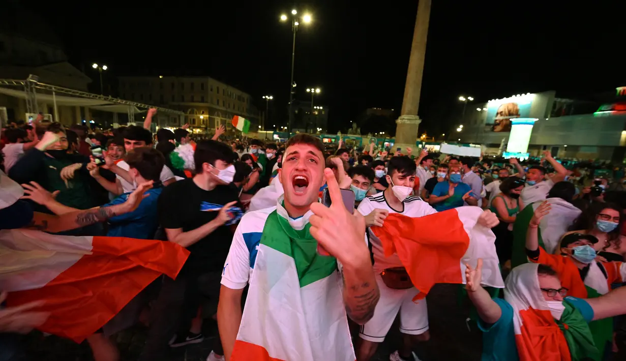 Fans bereaksi setelah timnas Italia mencetak gol kedua saat mereka menonton di layar raksasa dari zona penggemar resmi di Piazza del Popolo di Roma pada laga pertama grup A Euro 2020 /2021, Jumat (11/6/2021). Timnas Italia berhasil menang 3-0 atas Turki. (ANDREAS SOLARO/AFP)