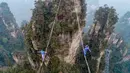 Dua kontestan berpakaian karakter Avatar berpacu sepanjang slackline di Pegunungan Huangshizhai di Zhangjiajie, Hunan, China, Minggu (23/12). Aksi tersebut dilakukan saat mengikuti slackline internasional.  (STR/AFP)
