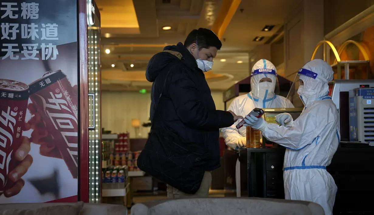 Seorang pekerja hotel dengan pakaian pelindung diri atau hazmat membantu seorang tamu membayar pembeliannya di Hotel Shangri-La pada Olimpiade Musim Dingin 2022, Rabu, 16 Februari 2022, di Beijing. (AP Photo/Jae C.Hong)