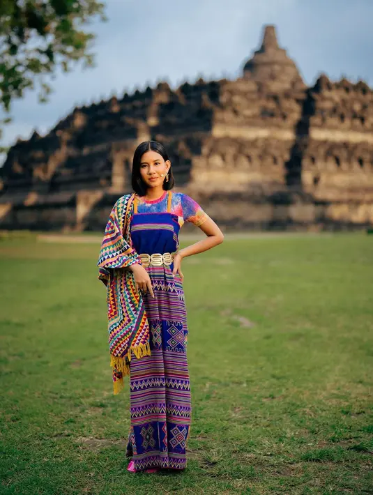 Ia tampil bergaya etnik modern dengan nuansa biru yang dipadukan bersama tie dye t-shirt dengan strap tenun dress berwarna biru. [Instagram/shenacinnamon].