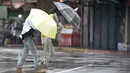 Dua wanita mengenakan payung berjalan melawan hembusan angin kencang yang ditimbulkan oleh topan Lekima di Taipei, Taiwan, Jumat (9/8/2019). Topan Lekima saat ini tengah menghantam Taiwan, membawa angin ribut dengan kecepatan 190 km/jam. (AP Photo / Chiang Ying-ying)