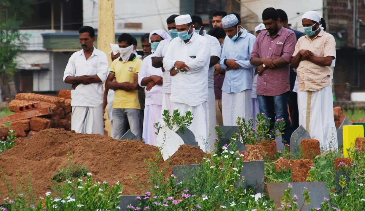 Keluarga dan kerabat memakai masker saat berdoa setelah penguburan jenazah yang tewas akibat terjangkit virus Nipah di Kozhikode, Kerala, India Selatan, Kamis (24/5). Wabah virus Nipah dimulai awal bulan ini di Kerala. (AP Photo/K.Shijith)