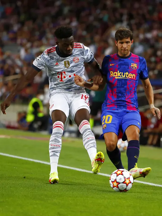 Pemain Bayern Munchen Alphonso Davies (kiri) berebut bola dengan pemain Barcelona Sergi Roberto pada pertandingan Grup E Liga Champions di Stadion Camp Nou, Barcelona, Spanyol, Selasa (14/9/2021). Bayern Munchen menang 3-0. (AP Photo/Joan Monfort)