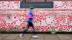 Seorang pelari melewati Tembok Memorial COVID di London, Senin (10/1/2022). Data menunjukkan, booster dosis kedua belum dibutuhkan karena saat ini vaksin dosis ketiga bagi orang di atas 65 tahun, telah memberikan perlindungan terhadap rawat inap sekitar 90 persen. (AP Photo/Kirsty Wigglesworth)