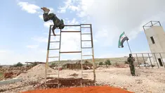 Pejuang dari Jaysh al-Izza (the Army of Glory) melompati rintangan saat melakukan latihan di kota Idlib, Suriah (9/4). Pejuang ini adalah afiliasi dari tentara Suriah yang didukung oleh Turki. (AFP/Omar Haj Kadour)