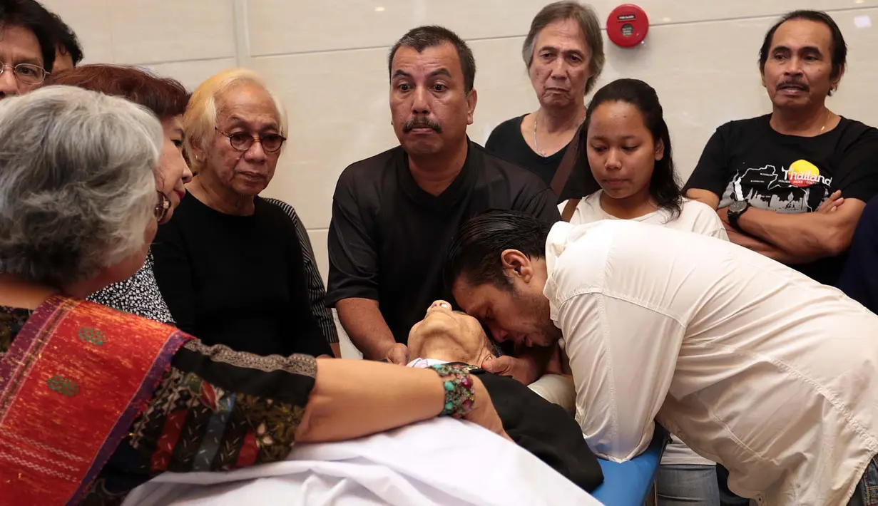 Kesedihan keluarga mengelilingi jenazah yang sedang disemayamkan di rumah duka Dharmais. Anak penyanyi senior Benny, Dino tak kuasa menahan kesedihannya sambil tertunduk di kepala ayahnya. (Deki Prayoga/Bintang.com)