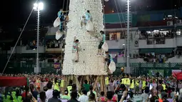 Peserta berlomba memanjat menara berlapis roti manis atau bakpao imitasi pada Festival Bun di pulau Cheung Chau, Hong Kong, Rabu (23/5). Mereka memasukkan bakpao itu sebanyak-banyaknya ke dalam karung yang dibawa sewaktu memanjat menara. (AP/Kin Cheung)