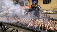 Relawan memanggang sate daging untuk hidangan buka puasa massal pada hari ke-15 bulan suci Ramadhan di pinggiran Matariya, timur laut Kairo, Mesir, 16 April 2022. (Khaled DESOUKI/AFP)
