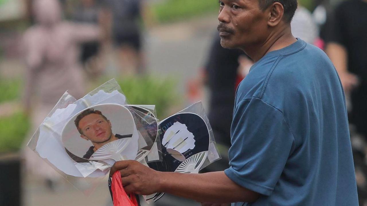 Seorang pedagang musiman menawarkan kipas bergambar Chris Martin, vokalis Coldplay, di sekitaran Gelora Bung Karno (GBK), Senayan, Jakarta, Rabu (15/11/2023). Konser Coldplay bertajuk 'Music of the Spheres Tour' yang berlangsung di Jakarta malam ini diman