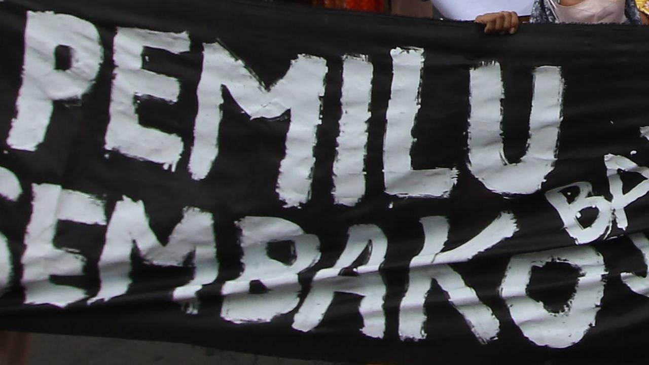 Emak-emak membentangkan spanduk hitam bertuliskan 'Pemilu banjir bansos, sembako jadi mahal'.&nbsp;Merdeka.com/Arie Basuki&nbsp;