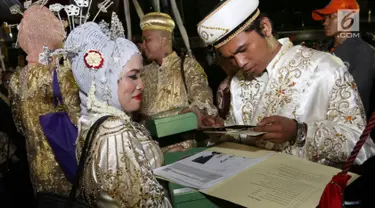 Sejumlah pasangan mengikuti nikah massal di malam pergantian tahun di Jalan MH Thamrin, Jakarta, Minggu (31/12). Sebanyak 430 pasangan melakukan nikah massal yang diselenggarakan oleh pemprov DKI Jakarta. (Liputan6.com/Angga Yuniar)