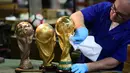 Pekerja membersihkan dengan kain replika trofi Piala Dunia FIFA di piala Italia dan pabrikan medali GDE Bertoni di Paderno Dugnano, Milan (11/4). Piala Dunia akan diselenggarakan 14 Juni sampai 15 Juli di Rusia. (AFP Photo/Miguel Medina)