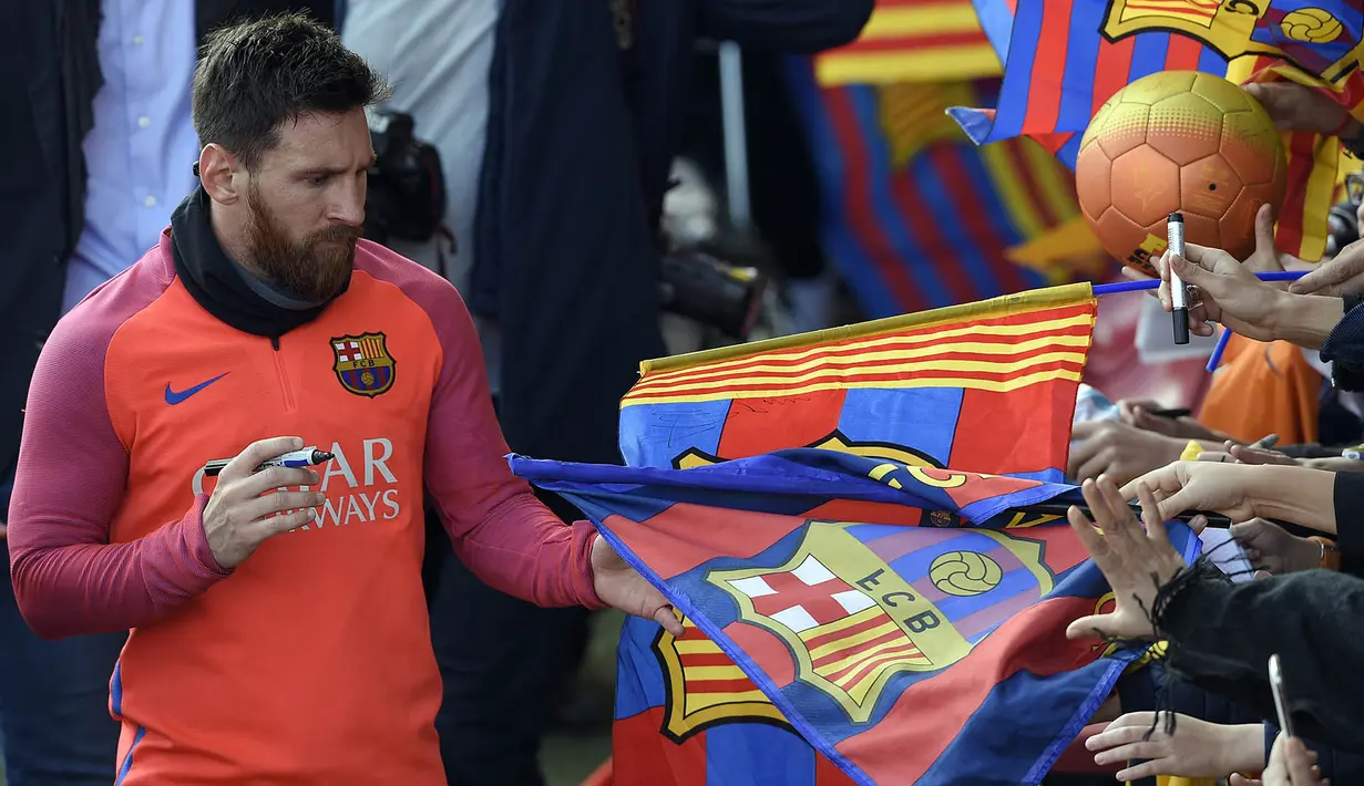 Bintang Barcelona, Lionel Messi, memberikan tanda tangan kepada fans usai mengikuti sesi latihan perdana tahun 2017. Selain La Liga, Barca juga masih berjuang untuk trofi Liga Champions tahun ini. (AFP/Lluis Gene)