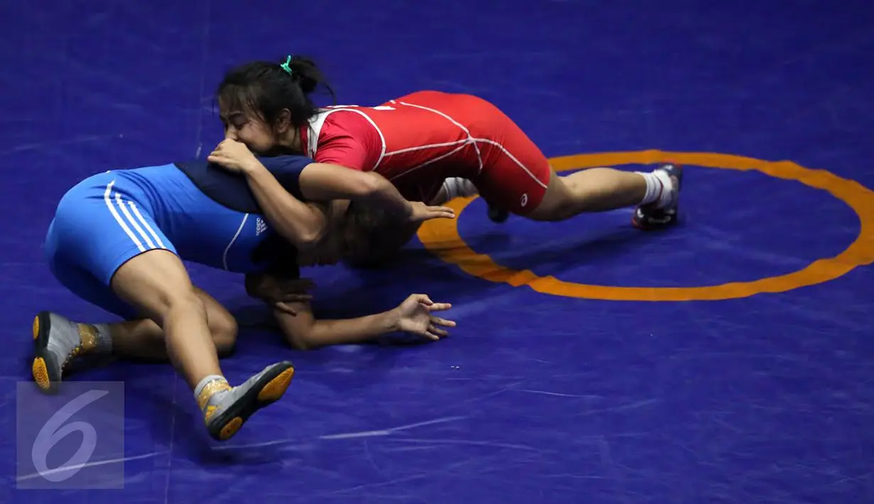 Pegulat putri Kaltim, Inadrah (kostum merah) melakukan teknik kuncian saat laga final gaya bebas kelas 53 kg putri pada PON XIX melawan pegulat putri Sumbar Mardiatul di Arena Saparua Sport Park, Bandung, Sabtu (24/9). (Liputan6.com/Helmi Fithriansyah)