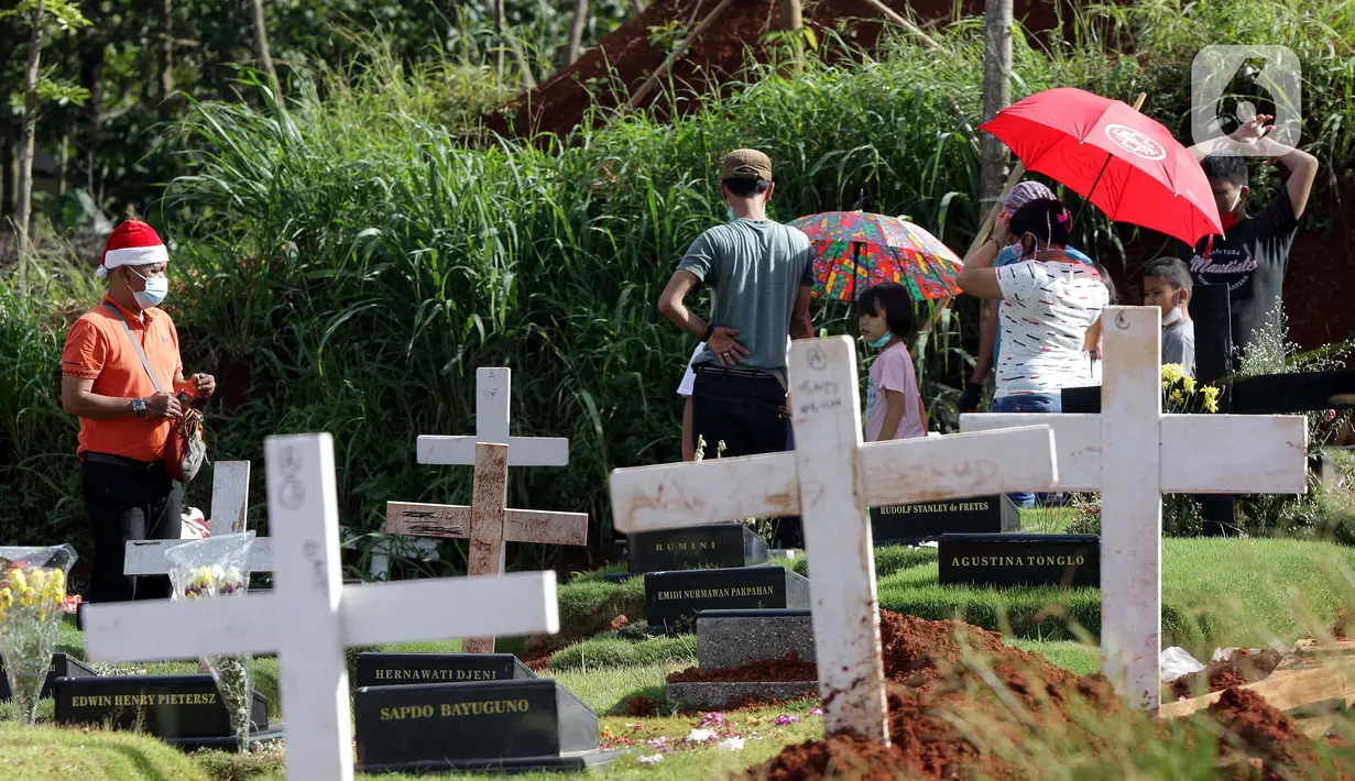 Warga melakukan ziarah di area pemakaman khusus dengan protokol COVID-19 di TPU Pondok Ranggon, Jakarta, Jumat (25/12/2020). Momen perayaan Natal 2020 dimanfaatkan sejumlah umat kristiani untuk berziarah mendoakan kerabat yang dimakamkan dengan protokol COVID-19. (Liputan6.com/Helmi Fithriansyah)