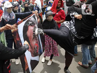 Pengunjuk rasa menendang poster bergambar Presiden Prancis Emmanuel Macron dalam aksi damai di kawasan Sarinah, Jakarta, Senin (2/11/2020). Massa demonstran dari gabungan elemen Islam mengecam pernyataan presiden Emmanuel Macron yang dianggap menghina Islam. (Liputan6.com/Faizal Fanani)