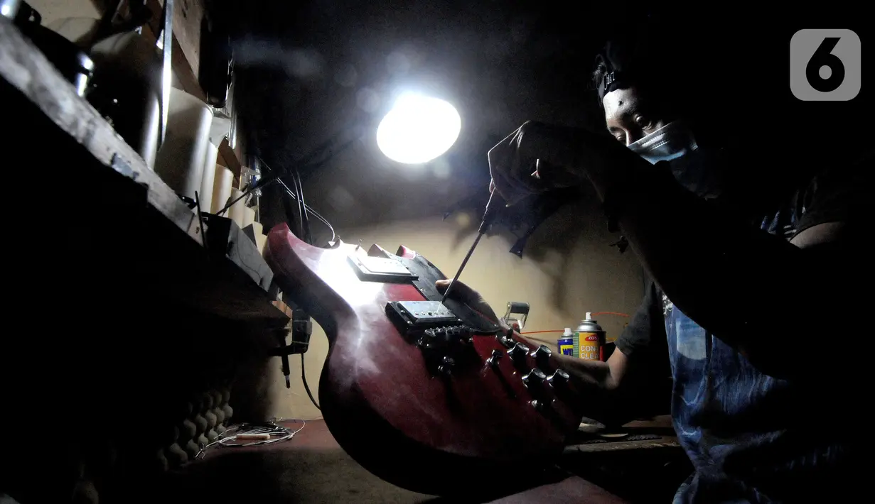 Pekerja menyelesaikan pembuatan gitar listrik Syukey Instrumen di kawasan Ciputat Timur, Tangerang Selatan, Banten, Selasa (26/10/2021). Pasca-PPKM, produksi gitar listrik mulai menggeliat kembali setelah selama dua tahun vakum dan hanya melayani service gitar. (merdeka.com/Arie Basuki)