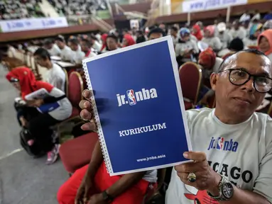Seorang guru olahraga menunjukkan buku kurikulum pelatihan pendidikan basket dari Akademi Pelatih Junior NBA di GOR Ciracas, Jakarta, Rabu (24/1). Pendidikan ini ditujukan kepada lebih dari lima ribu guru olahraga di Jakarta. (Liputan6.com/Faizal Fanani)
