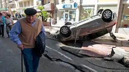 Seorang pria berjalan melewati mobil yang terbalik dan jalanan yang hancur akibat banjir di Cannes, Prancis, Minggu (4/10/2015). Akibat peristiwa itu, sebanyak 16 warga dilaporkan tewas. (REUTERS/Eric Gaillard)