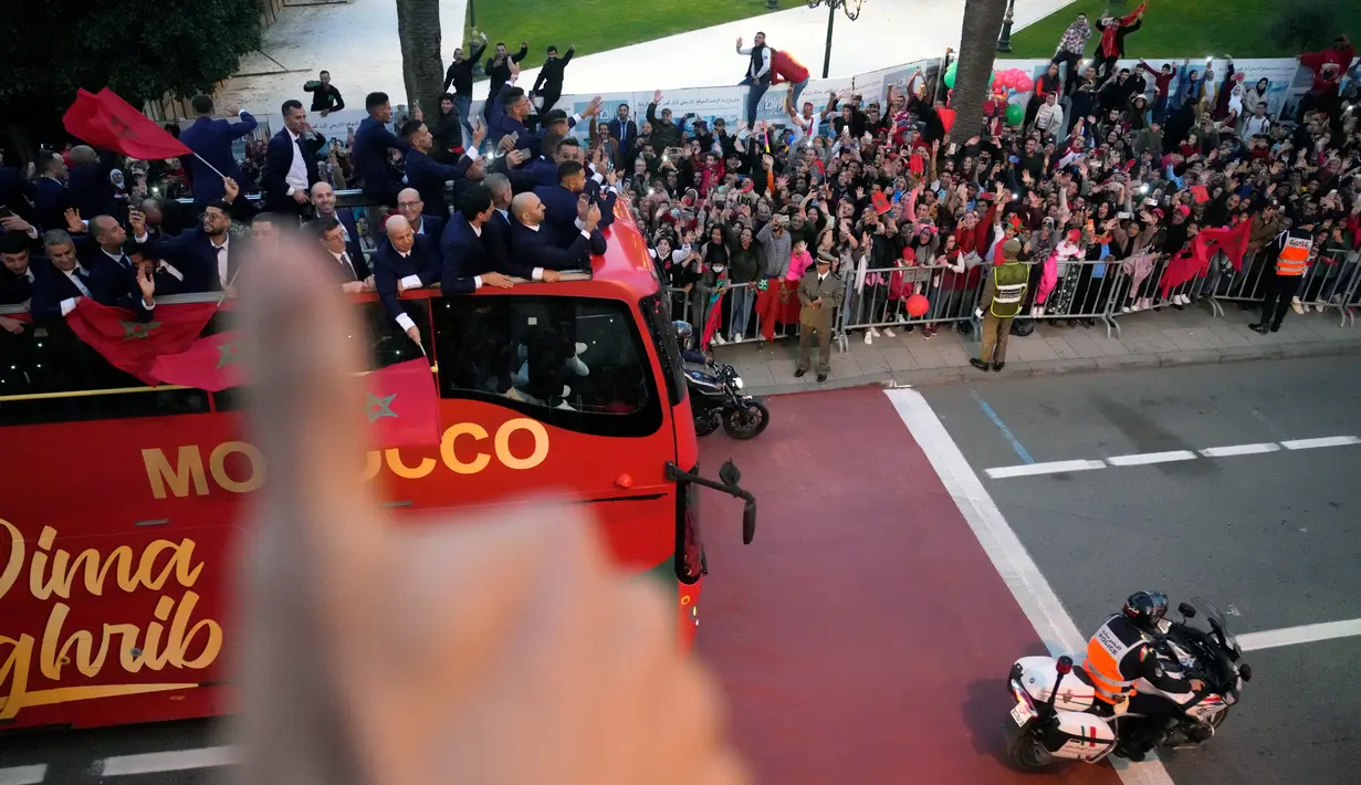 <p>Para pemain Timnas Maroko melakukan selebrasi di atas bus dan melambaikan tangan ke publik saat parade di Rabat , Maroko, 20 Desember 2022. Timnas Maroko mendapat sambutan hangat di negaranya setelah berhasil meraih juara keempat Piala Dunia 2022. (AP Photo/Mosa'ab Elshamy)</p>
