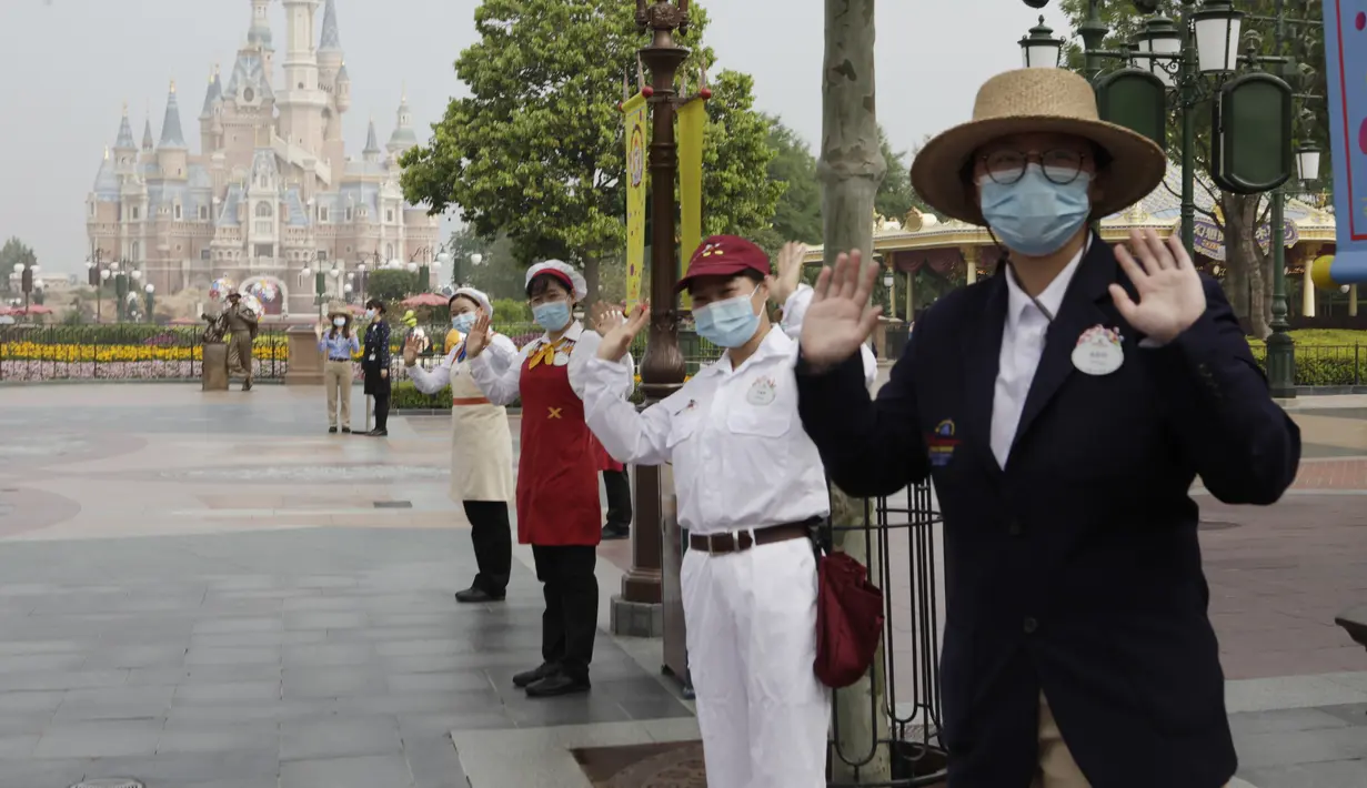 Pegawai mengenakan masker saat menyambut wisatawan di taman hiburan Disneyland, Shanghai, China, Senin (11/5/2020). Disneyland Shanghai kembali dibuka setelah tiga bulan ditutup akibat pandemi virus corona COVID-19. (AP Photo/Chen Si)