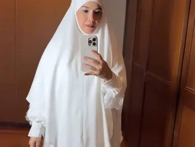 Gaya hijab yang dikenakan Annisa Pohan dalam foto ini adalah model mukena berwarna putih polos dengan desain sederhana namun elegan. Mukena ini memiliki potongan yang longgar dan nyaman, dengan aksen renda di bagian bawah yang menambah kesan anggun. (Liputan6.com/IG/@annisayudhoyono)