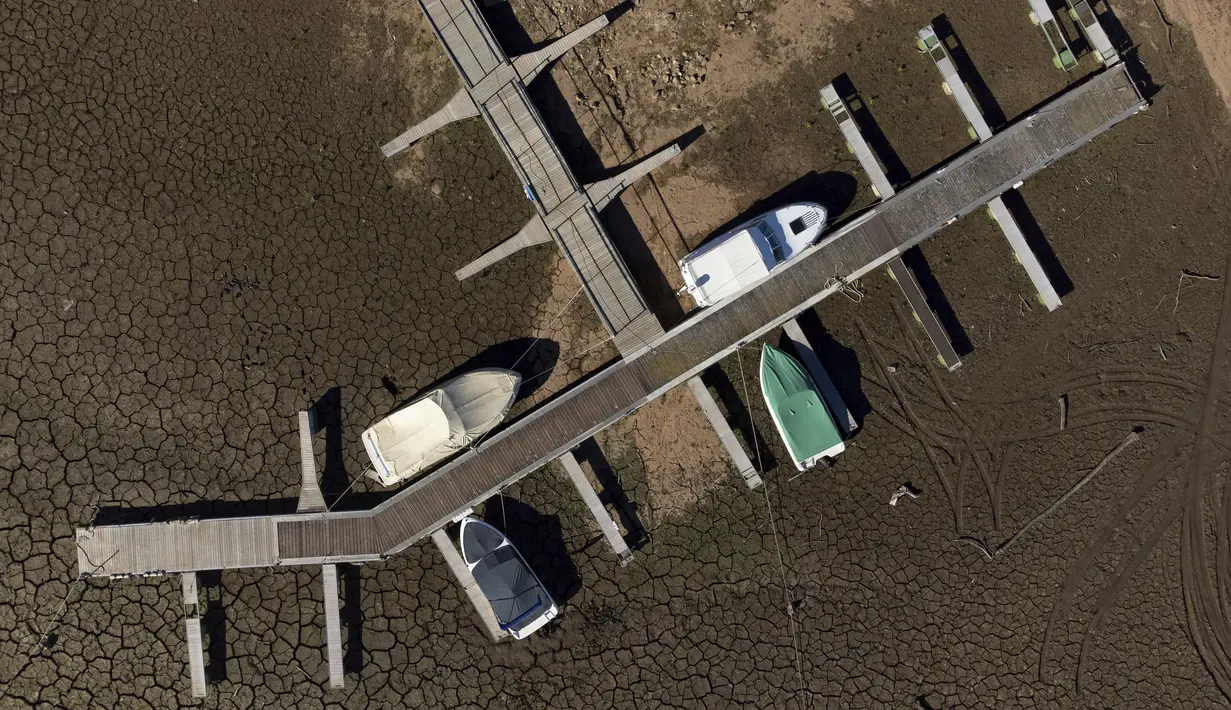 Dalam gambar udara dengan drone, kapal pesiar yang diikat ke dermaga beristirahat di tanah kering dari air yang habis di Sungai Zezere karena kekeringan, dekat Figueiro dos Vinhos di Portugal, 17 Februari 2022. Portugal telah mengalami minim curah hujan sejak Oktober lalu. (AP/Sergio Azenha)