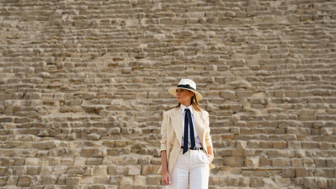 Ibu Negara AS Melania Trump saat berkunjung ke situs bersejarah Piramida Giza dekat Kairo, Mesir (6/10). Melania tampil mengenakan busana safari klasik dengan blazer warna krem di atas kemeja putih, dasi hitam, dan celana krem. (AP Photo/Carolyn Kaster)