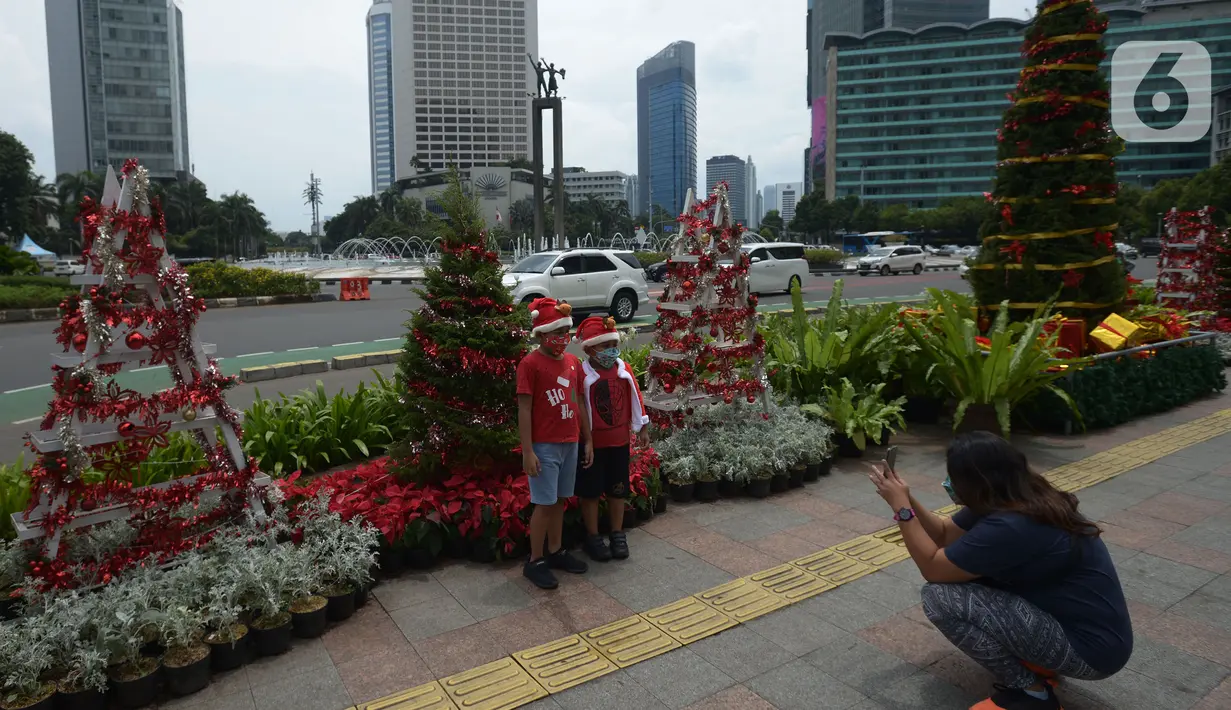 Anak-anak berpose dengan latar hiasan pohon Natal 2021 di Bundaran HI, Jakarta, Sabtu (25/12/2021). Libur Natal 2021 dimanfaatkan sebagian warga berfoto berlatar pohon Natal yang telah dihias atau berjalan-jalan ke mal untuk mengisi waktu berlibur bersama. (merdeka.com/Imam Buhori)