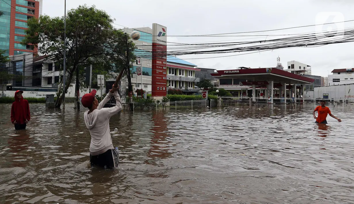 Warga bermain bola saat banjir merendam kawasan Green Garden, Jakarta Barat, Selasa (25/2/2020). Hujan yang mengguyur kawasan Jakarta membuat kawasan tersebut tergenang banjir setinggi 60-80 cm. (Liputan6.com/Johan Tallo)