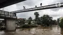 Anak-anak melompat ke Sungai Ciliwung saat banjir melanda Jalan Bina Warga Rt 005/Rw 07 Kelurahan Rawa Jati, Jakarta, Senin (8/2/2021). Banjir setinggi 60-190 cm tersebut disebabkan oleh luapan air Sungai Ciliwung dan curah hujan Jakarta yang tinggi. (Liputan6.com/Johan Tallo)