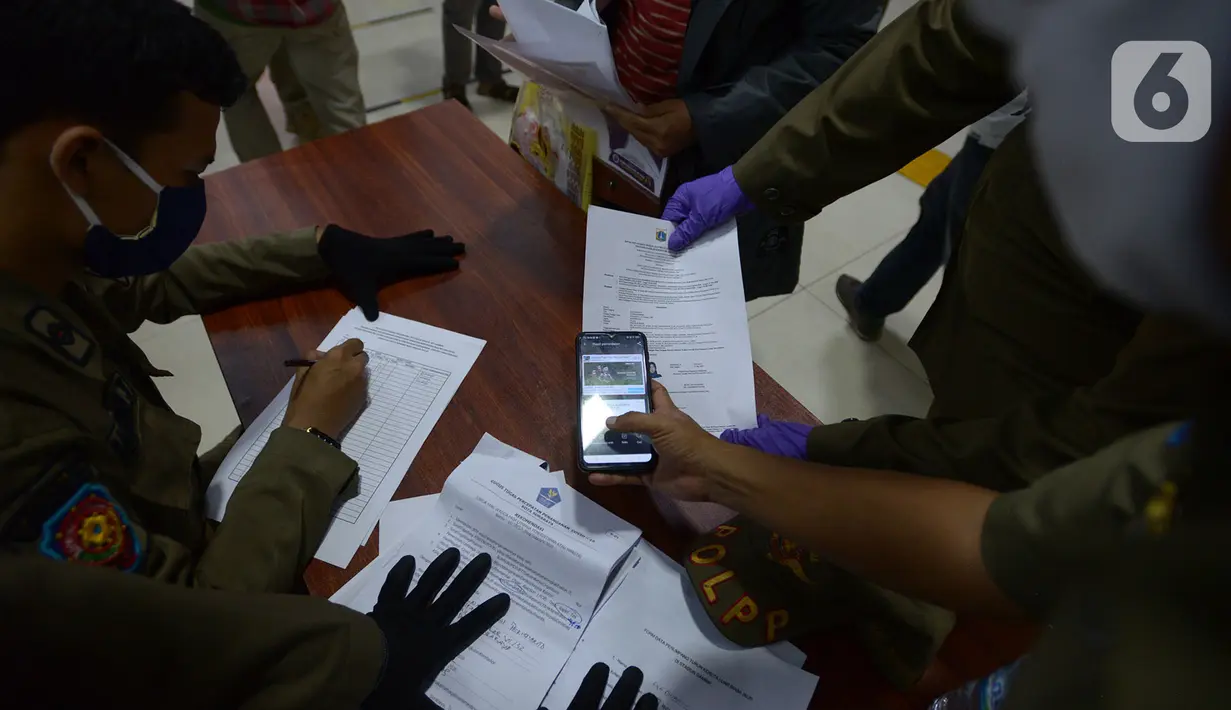 Petugas mengecek SIKM milik penumpang di stasiun Gambir Jakarta, Kamis (28/5/2020). Penumpang yang mudik dari Surabaya mengunakan kereta api luar biasa harus memiliki SIKM sebagai syarat yang dimiliki warga untuk keluar atau masuk ke wilayah Jakarta. (merdeka.com/Imam Buhori)