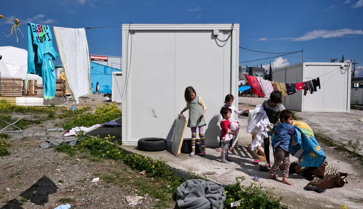 Sejumlah anak pengungsi bermain di depan Kamp Oinofyta, Athena, Yunani (13/3). Kamp Oinofyta yang merupakan gedung bekas pabrik. (AFP Photo / Louisa Gouliamaki) 