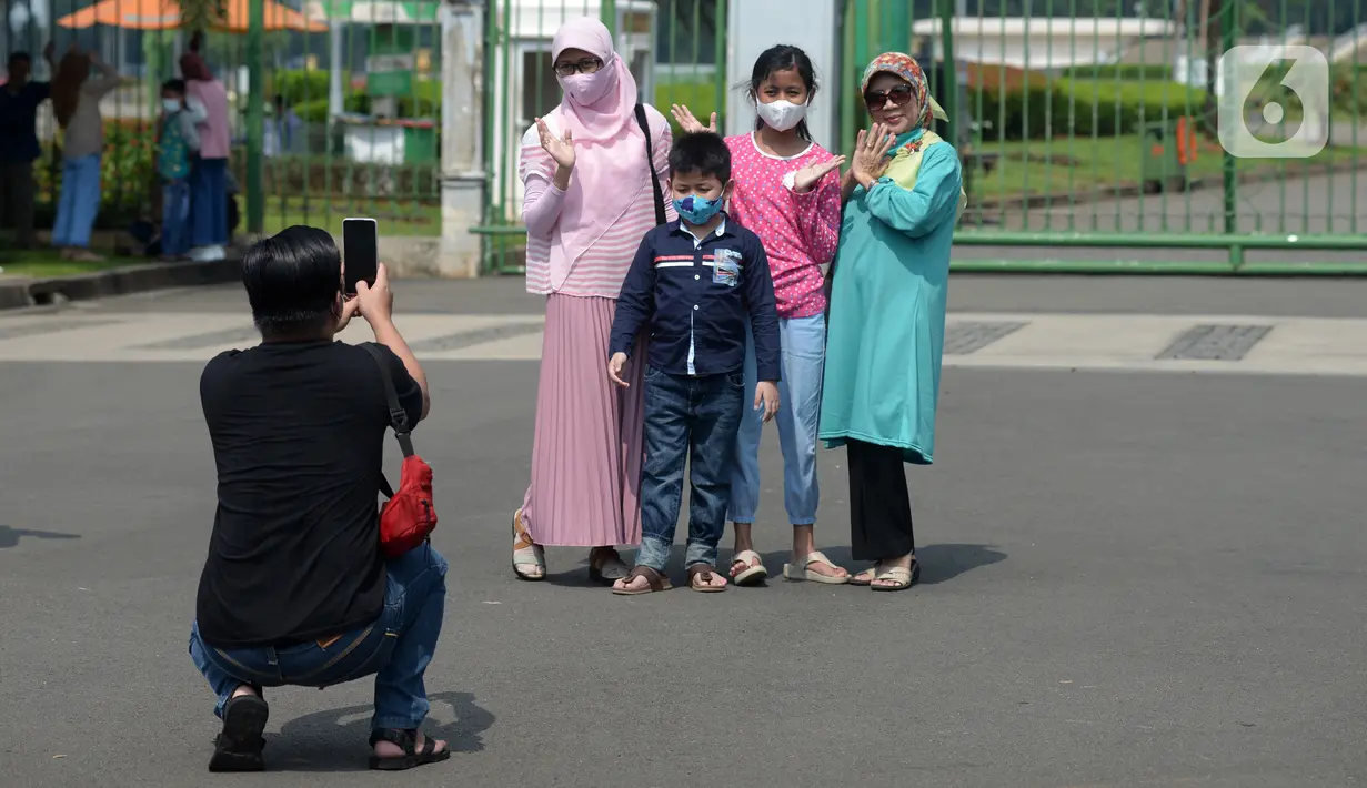 Warga berfoto di depan pagar Monumen Nasional (Monas), Jakarta, Sabtu (15/5/2021). Warga kecewa lantaran tempat wisata tersebut ditutup, padahal mereka datang untuk menikmati libur Idul Fitri 1442 Hijriah. (merdeka.com/Imam Buhori)