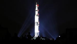 Orang-orang menyaksikan proyeksi roket NASA, Saturn V, di Monumen Washington menandai peringatan 50 tahun misi Apollo 11 ke bulan di National Mall, Washington, Selasa (16/7/2019). Pada 16 Juli 1969, NASA mencatatkan sejarah dengan melakukan peluncuran Apollo 11. (Mark Wilson/Getty Images/AFP)
