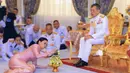 Raja Maha Vajiralongkorn (kanan) melihat ke arah Ratu Suthida saat prosesi pernikahan mereka di Bangkok, Thailand, Rabu (1/5/2019). Sebelumnya, Raja Thailand tersebut telah menikah dan bercerai tiga kali dengan menghasilkan tujuh orang anak. (Thai TV Pool via Reuters)