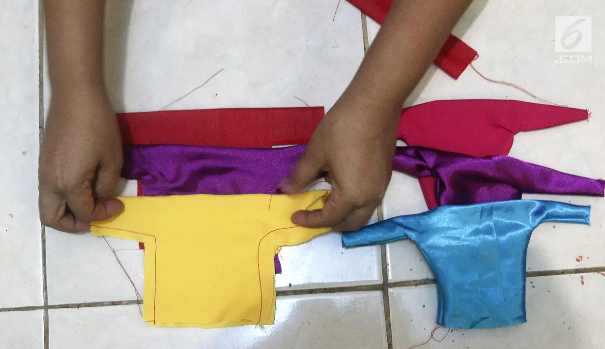 Perajin, membuat baju untuk miniatur ondel-ondel dari botol plastik di rumah produksi Kramat Jati, Jakarta, Rabu (28/11). Miniatur yang terbuat dari plastik diproduksi 50-80 buah dengan omset 5-8 Juta perbulan. (Liputan6.com/Herman Zakharia)