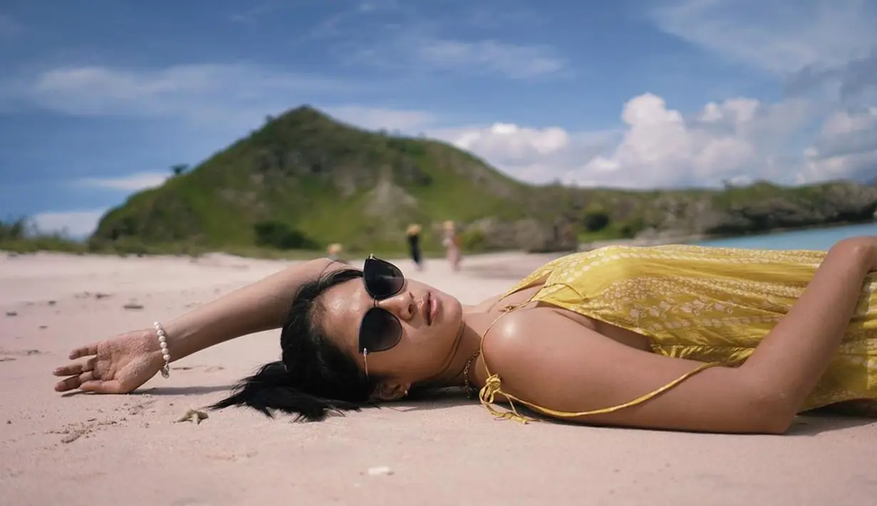 Tidur di atas pasir pantai sembari menikmati langit dan deburan ombak, tentunya dapat membantu melepas penat dari padatnya aktivitas syuting. Tidak takut warna kulitnya berubah, Hana Saraswati terlihat menikmati pantai sebagai salah satu tempat favorit untuk liburan (Liputan6.com/IG/@hanahaho)