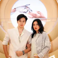 Angga tampil gagah dengan set kemeja dan trousers yang dipadukan dengan long coat warna sand. Serta disempurnakan dengan kalung Bulgari.