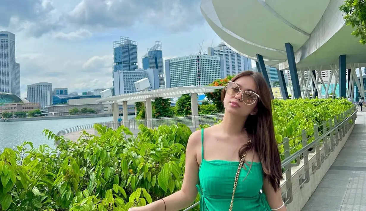 Gaya berlibur yang manis dari Rebecca Klopper. Ia tampil mengenakan strappy dress hijau dengan detail serut di sisi kanan-kiri. Foto: Instagram.
