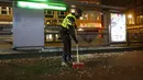 Seorang petugas polisi menyapu kaca dari halte bus yang dihancurkan dalam protes terhadap jam malam nasional di Rotterdam, Belanda, Senin (25/1/2021).  Bentrokan terjadi di beberapa lokasi di Belanda, termasuk di Amsterdam, akibat kebijakan jam malam untuk mencegah COVID-19. (AP Photo/Peter Dejong)