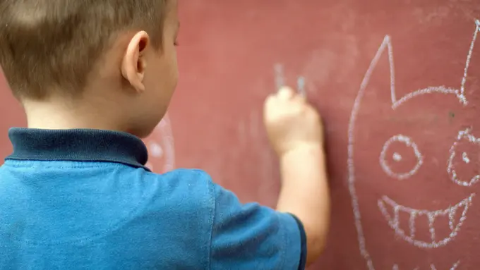 Anak sedang menggambar di dinding