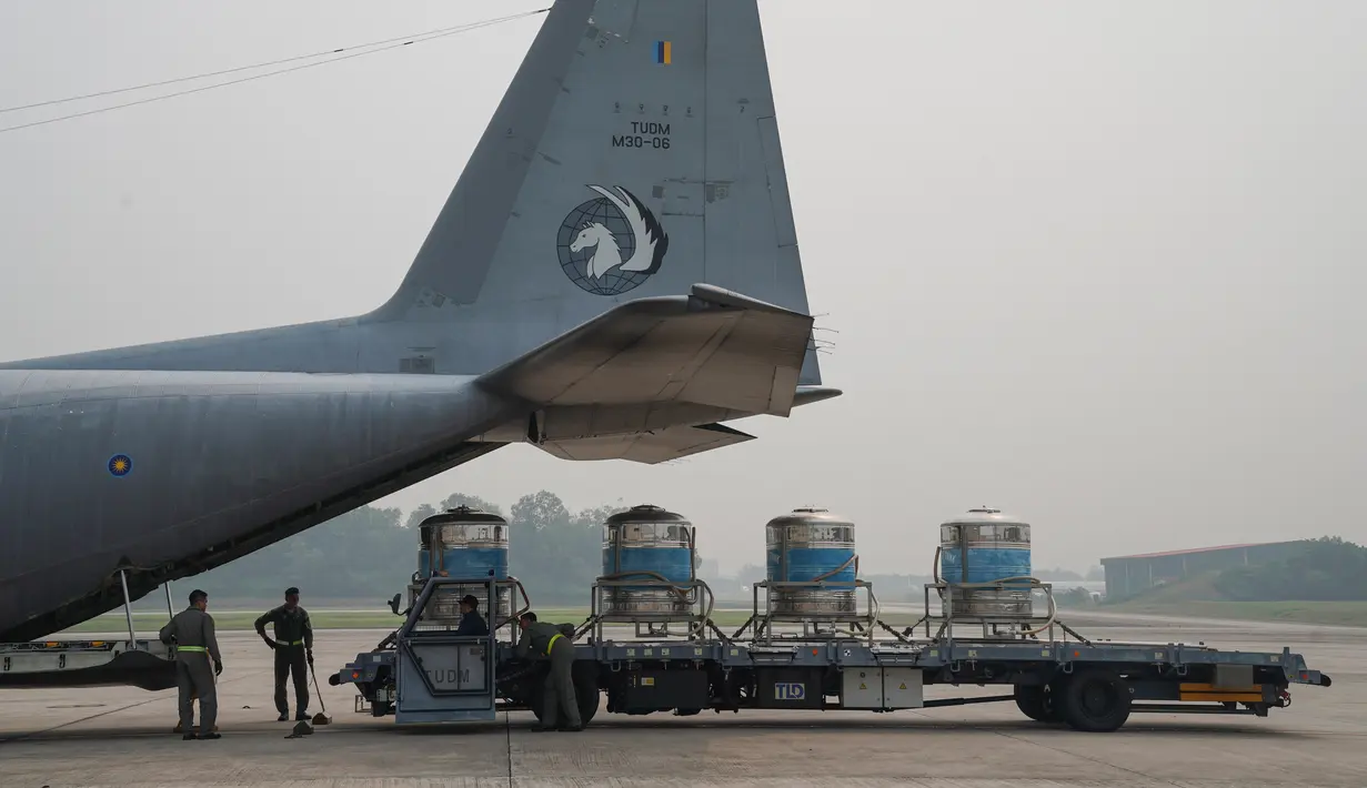 Tangki berisi larutan air garam dimasukkan ke dalam pesawat saat akan proses penyemaian awan di Pangkalan Udara Militer Subang, Malaysia, Kamis (19/9/2019). Malaysia melakukan operasi penyemaian awan untuk mendorong hujan dalam mengatasi kabut asap yang melanda. (AP Photo/Vincent Thian)
