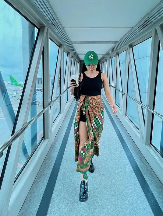 Saat di bandara, Yura juga terlihat keren memadukan tanktop hitam dengan kain batik berwarna hijau. [instagram/yurayunita]
