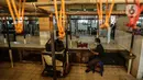 Seorang pria bermain smartphone di los pedagang yang kosong di Pasar Kebayoran, Jakarta, Rabu (20/1/2021). Para pedagang daging sapi di sejumlah pasar di kawasan Jakarta, Bogor, Depok, Tangerang, dan Bekasi (Jabodetabek) menggelar aksi mogok jualan hingga Jumat (22/1). (Liputan6.com/Johan Tallo)
