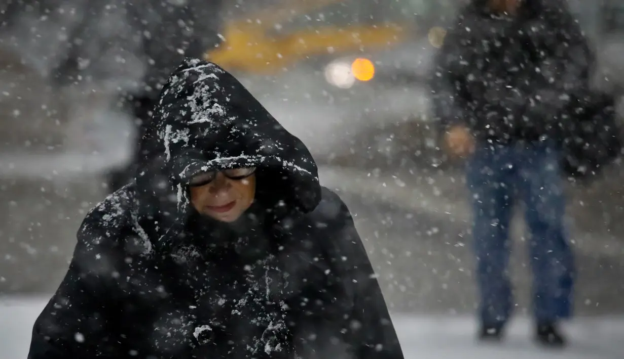 Pejalan kaki menghadapi hujan salju yang turun di Manhattan, New York, Kamis (15/11). Salah satu badai besar pertama musim ini bergerak melintasi bagian timur negara tersebut pada Kamis ini. (AP/Bebeto Matthews)