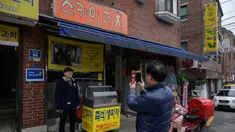 Seorang pria berpose di depan foto sutradara film Bong Joon-ho di restoran pizza bernama 'Sky Pizza' di Seoul, 13 Februari 2020. Lokasi syuting Parasite di Korea Selatan semakin ramai dikunjungi turis setelah film tersebut berhasil memboyong dan mendominasi di penghargaan Oscar 2020. (Ed JONES/AFP)