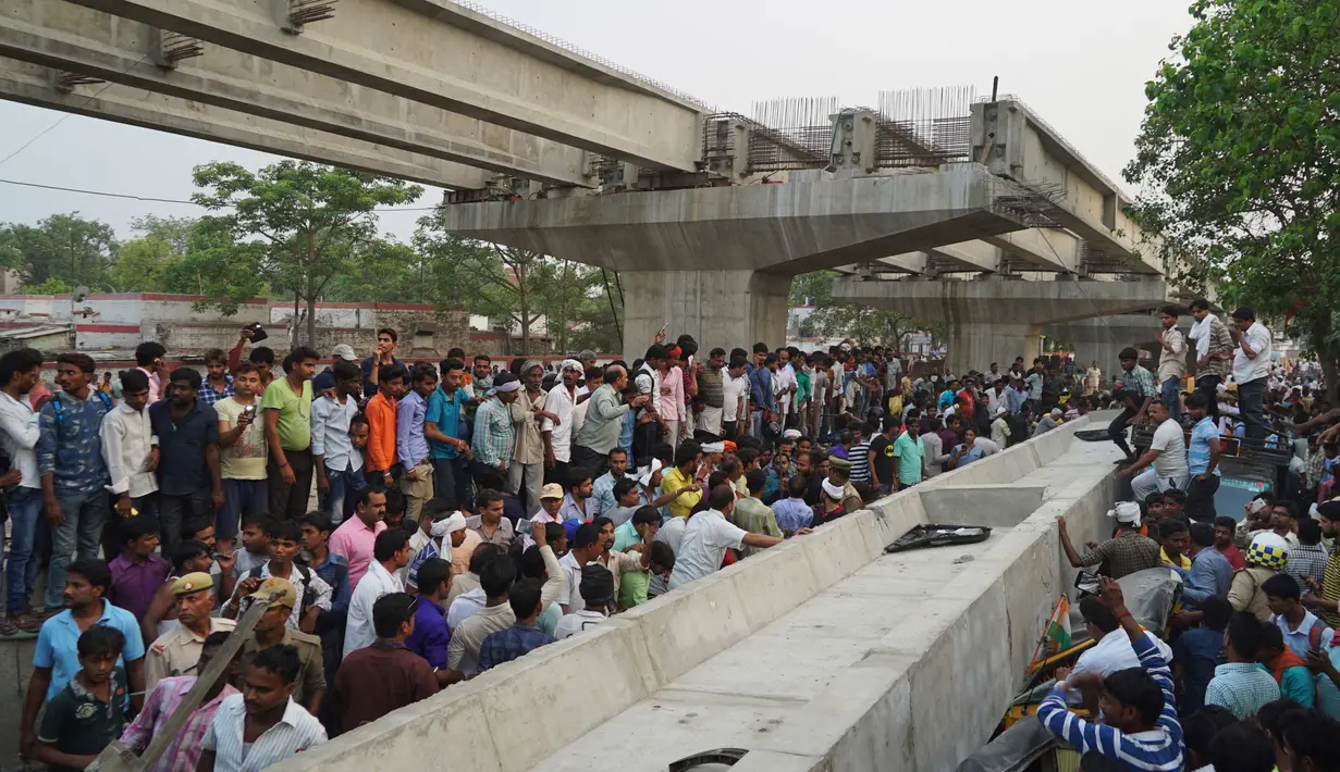 Warga India berusaha menyelamatkan korban yang terperangkap akibat runtuhnya jalan layang di Varanasi, Selasa (15/5). Material jalan layang yang memiliki berat berton-ton itu menimpa dan menghancurkan sejumlah kendaraan di bawahnya. (AP Photo)