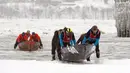 Tim Volvo yang dilewati oleh Benoit Gilbert bergerak dari air sedingin es ke atas es untuk memenangkan perlombaan kano es Karnaval Musim Dingin Quebec melintasi Sungai St. Lawrence di Kota Quebec, Kanada, 5 Februari 2023. Tim Chateau Frontenac, dilewati oleh Jean Anderson (belakang), menempati posisi kedua. (Jacques Boissinot/The Canadian Press via AP)