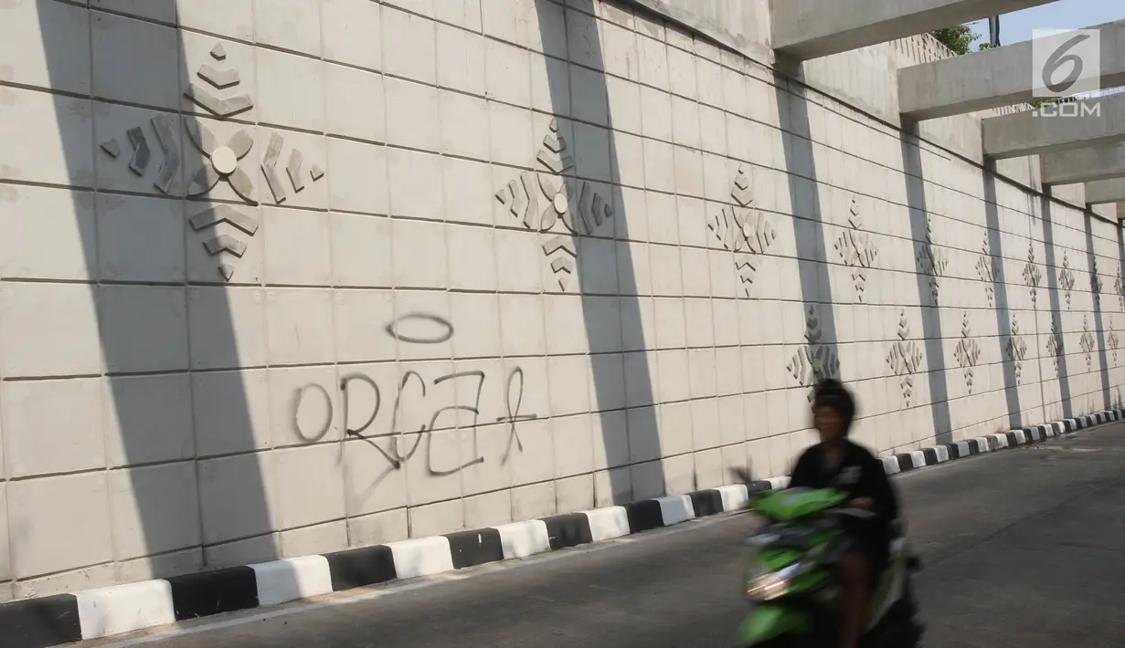 Pengendara motor melintasi coretan di dinding underpass atau lintas bawah Matraman, Jakarta Selatan, Rabu (2/5). Underpass yang belum genap sebulan diresmikan untuk diuji coba tersebut dihiasi coretan tangan jahil. (Liputan6.com/Arya Manggala)